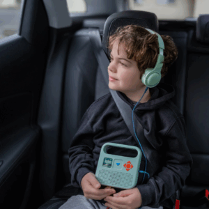 Un enfant en voiture à écouter la Merlin avec son casque audio.